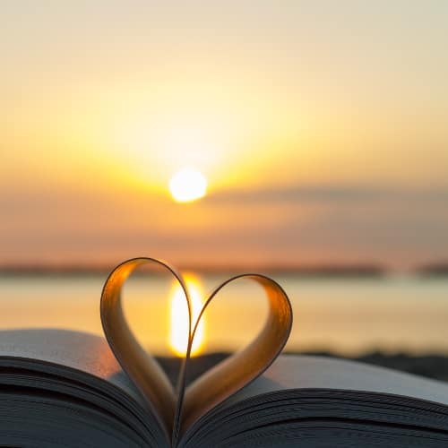 Heart shape formed by book pages at sunrise symbolizing love, hope, and reflection